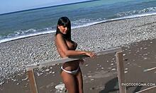 O adolescentă brunetă cu sâni falși uriași pozează chiar pe plajă