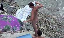 Mörkhårig amatör i nyanser är naken på en strand